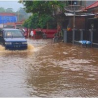 Nampak sebuah kendaraan berusaha melewati jalan yang terendam banjir.